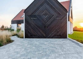 Na tę siedzibę składają się dwa umieszczone obok siebie i połączone przejściem obiekty: pierwszy, większy, to część mieszkalna, usytuowana na dwóch kondygnacjach, a w drugiej, przypominającej wiejską komórkę czy budynek gospodarczy, zlokalizowano garaż. Bramę garażu stworzono z desek z ciemnego modrzewia syberyjskiego, ułożonych w masywny wzór geometryczny, w którym na pierwszy rzut oka trudno dostrzec uchylne skrzydła