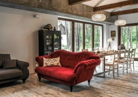 JADALNIA. Na granicy jadalni i części wypoczynkowej stoi reprezentacyjna pikowana kanapa. Żywy kolor mebla wybrano specjalnie, by przełamać wszechobecne brązy i szarości.