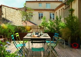 Rozległy taras wychodzi na patio. Krzesła Bistro (Fermob), drewniana zabudowa dla roślin i ławki to dzieło pana domu.