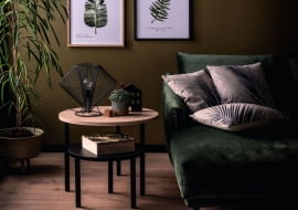 Botaniczne motywy na plakatach, zieleń ściany i sofy, drewniana podłoga oraz żywe rośliny – to wszystko tworzy we wnętrzu niepowtarzalny klimat, przypominający leśny zakątek. Galeria Wnętrz Domar/Meble Vox