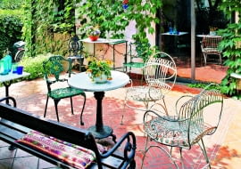 NA TARASIE jak w rzymskim patio: terakotowa posadzka, kute białe fotele z Włoch, stolik z kamiennym blatem (wyciętym przez zaprzyjaźnionego artystę).