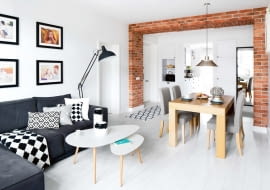 Jasno, słonecznie, a najważniejsze - przestronnie. W czasie remontu zniknęły niektóre ściany, a wraz z nimi typowy przedpokój. Przez drzwi wejściowe wchodzi się teraz bezpośrednio do jadalni. Cegła symbolicznie zaznacza miejsce, gdzie do niedawna stała jedna ze ścian dzielących mieszkanie na małe pomieszczenia.