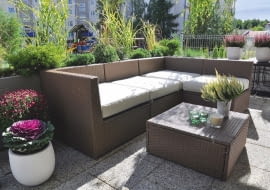 WZDŁUŻ AŻUROWEJ BARIERKI tarasu rosną iglaki w donicach i trawy ozdobne posadzone w skrzyniach.