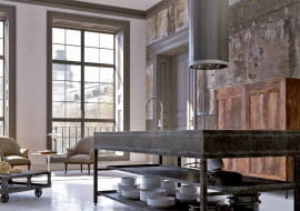 Okap kolumna. Corinthia Isola to propozycja dla osób ceniących wyrafinowane przedmioty. Ten cylindryczny okap wyspowy ma niezwykły kształt - pomiędzy kołem a wielokątem. Światło załamuje się na krawędziach, dzięki czemu tworzy złudzenie wielu odcieni szarości. Wykończenie powierzchni nawiązuje do żłobkowanego trzonu antycznej kolumny. Faber, faberspa.com