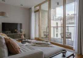 Salon otwierający się na loggię poprzez panoramiczne przeszklenie  to wymarzone miejsce  do przesiadywania i podpatrywania miejskich widoków.