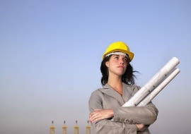 Woman in hard hat holding drafts with towers in background --- Image by cultura/Corbis