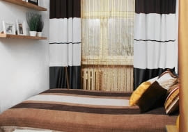 W latach osiemdziesiątych pokój nastolatka, później domowe biuro. Dziś małżeńska sypialnia - niewielka, ale przytulna, utrzymana w stonowanej kolorystyce ożywionej złotymi akcentami. <BR /> METAMORFOZA SYPIALNI. Najdroższym zakupem było łóżko. Niektóre meble - szafę oraz blaty stolików nocnych, zamocowane wspornikami do ściany - zrobiono z płyt MDF pozyskanych ze starej meblościanki. W domu znalazła się też tkanina podszewkowa, która zastępuje fronty szafy. Niewiele kosztowała również dekoracja okna. Leżąca w pokoju wykładzina dywanowa została przykryta bambusowymi matami. Za firanę posłużył kawałek tkaniny kupionej na wyprzedaży. Natomiast zasłonki to dawny zakup, który czekał na lepsze czasy. <BR /> KOSZT 1707 zł.