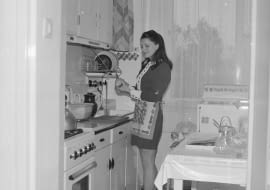 Danuta Krotowicz obiera gruszkę w kuchni. Widoczna kuchenka gazowa 'Warta', zlew i suszarka do naczyń.