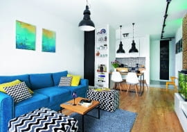 POKÓJ DZIENNY, otwarty na kuchnię i przedpokój, wygląda na przestronniejszy, niż jest w rzeczywistości. Stoją tu tylko kanapa z pufami (Rafek Meble), stolik kawowy (Take me Home) oraz niewielki regał i szafka RTV (zrobione na wymiar przez stolarza). Oszczędny wystrój urozmaicają plamy kolorów, wyraziste wzory i obrazy namalowane przez siostrę gospodarza.