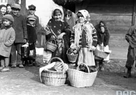 Obchody Wielkanocy straciły na swej pierwotnej wyrazistości. W ten okres wkrada się coraz więcej komercji, a we współczesnych zabieganych czasach traktujemy go jako okazję na odpoczynek, może nawet krótki wyjazd wypoczynkowy. Odchodzimy od tradycyjnych obrzędów, których młode pokolenia już nawet nie znają, a przynajmniej znaczna część młodych. Nie tak to jednak wyglądało kilkadziesiąt lat temu. Pielęgnowanie tradycji i kultywowanie rozmaitych obrzędów oraz zwyczajów było niezwykle ważnym elementem obchodów Wielkanocy. Te zmiany pokazują archiwalne zdjęcia ze zbiorów Narodowego Archiwum Cyfrowego. Większość została wykonana w latach 30., ale są też fotografie z czasów PRL-u. <br/> <b>Na zdjęciu:<b> Dziewczynki z koszami ze święconką przed dworem w Tomaszowicach 1937 rok