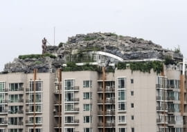 This Aug. 12, 2013 photo released by Chinas Xinhua News Agency shows a residential building with a rocky style villa on its roof, in Haidian District of Beijing, China. Beijing authorities are planning to demolish the bizarre rooftop villa embedded in rocks, trees and bushes that allegedly was built illegally atop a 26-story apartment block in the capital. (AP Photo/Xinhua, Luo Xiaoguang) NO SALES