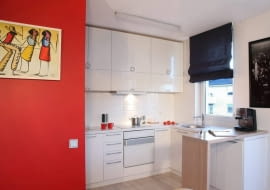 Właściciele oczekiwali od projektantów rozwiązań nietypowych i oryginalnych. Najbardziej wyrazistym elementem wystroju stał się tu kolor czerwony, który w różnym natężeniu pojawia się niemal we wszystkich pomieszczeniach. <BR /> MIESZKANIE. Aneks kuchenny został celowo 'wyczyszczony' z mocnych kolorów - szafki z lakierowanej na biało płyty MDF wtapiają się w tło ścian w tym samym kolorze, dzięki czemu nie rzucają się w oczy (to ważne, gdy kuchnia jest połączona z pokojem dziennym). Prosty barek z bielonego litego dębu służy jako blat roboczy i jako miejsce na mały posiłek czy szybką kawę.