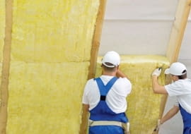 Układanie pierwszej warstwy ocieplenia; wełna powinna ciasno leżeć między krokwiami, ale nie wypychać folii do góry