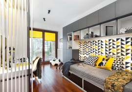 PO ZMIANIE. Wygodny tapczan stoi w tym samym miejscu co poprzedni, tyle że zmieniło się otoczenie mebla - pojawiła się zabudowa z szafkami i otwartymi półkami. Podobnie jak pozostałe meble zrobiono ją na zamówienie z płyty laminowanej w szarym i białym kolorze.