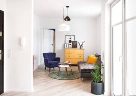 Z ZASKOCZENIA: ten widok pokoju dziennego nie zapowiada jeszcze feerii kolorów. Chyba że zajrzymy za ściankę, na której wisi domofon (po drugiej stronie stoi czerwona szafka). Albo uchylimy drzwi do sypialni pomalowanej na kobaltowy kolor.