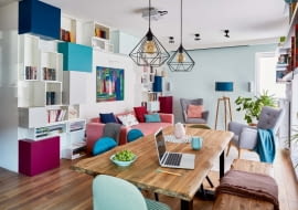 Do kolorystyki regału z pojemnymi schowkami i otwartymi półkami nawiązują odcienie poduszek. Na półkach jest jeszcze trochę wolnego miejsca na książki. Za listwą pod sufitem znajduje się rozwijany ekran - Justyna ogląda na nim filmy z rzutnika zamontowanego na środku sufitu.