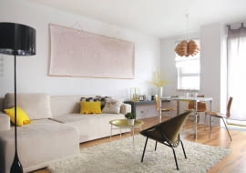 Tradycyjny układ mieszkania, z osobnymi zamkniętymi pomieszczeniami, nie przypadł gospodarzom do gustu. Marzyło im się otwarte wielofunkcyjne wnętrze, pełne przestrzeni i światła. Swoją wizję zrealizowali, wyburzając lub przesuwając większość ścian. Zobaczcie efekt. <BR /> MIESZKANIE. Niebanalna dekoracja nad kanapą to kawałek tapety z koronkowym wzorym, usztywniony dwiema listewkami.  Na podłogę wybrano panele imitujące bielony dąb.