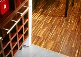 Między parkietem a płytkami ceramicznymi ułożono tzw. listwę dylatacyjną. Zakrywa ona szczelinę - niezbędną w tym miejscu, by drewno mogło 'pracować'. Projekt wnętrza: Radosław Guzowski