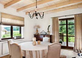 <B>Wnętrze zostało urządzone w rustykalnym stylu, dlatego pani domu udekorowała okna prosto drapowanymi zasłonami z lnianego płótna. Aranżacja jest równie naturalna i piękna jak Puszcza Knyszyńska widoczna na horyzoncie.</B> <BR />Długie zasłony w drzwiach balkonowych i rolety w oknie uszyto z grubego, gęsto tkanego lnu. Pani domu tak podoba się ten rodzaj tkaniny, że wybrała ją także na obicia krzeseł, obrus oraz abażur lampy.