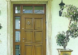 Jasna kolorystyka elewacji to również jasne drzwi. Ich urodę podkreśla ozdobne obramowanie drzwi i przeszklona ścianka.