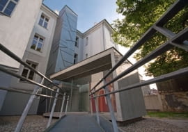 Pawilon z windą dla niepełnosprawnych przy bocznym wejściu do budynku Zespołu Szkół Ogólnokształcących nr 10 w Gliwicach.