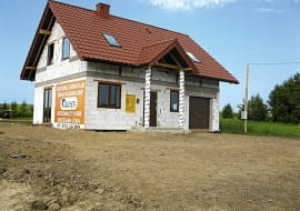 Dom ulokowany jest w odległości 4 m od płotu z jednej strony i niewiele większej z drugiej. Teren dokoła jest pusty i płaski, a wejście zwrócone na południe.