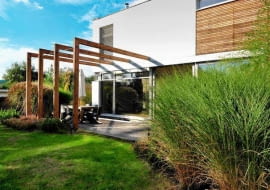 Konstrukcja pergoli podkreśla podział przestrzeni tarasu na dwie strefy: zadaszoną jadalnię i słoneczną plażę.