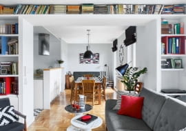 CO ZA PERSPEKTYWA! Po połączeniu dwóch mieszkań powstała przestronna strefa dzienna. Szerokie przejście z salonu do jadalni obudowano płytami gipsowo-kartonowymi, tak by powstały półki na książki oraz miejsce do pracy (jedna z półek wystaje, można na niej wygodnie położyć laptop).