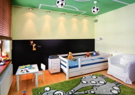 <B>Zamiast kupować kolejną zabawkę, dającą radość na dwa dni, podarujmy dziecku nowy wystrój jego pokoju. Taki, który stworzy maluchowi nie tylko wspaniałe warunki do zabawy, ale i możliwość rozwoju zainteresowań oraz wyrobi w nim poczucie estetyki. Choćby taki jak ten.</B> <BR />Największą atrakcją pokoju jest bez wątpienia boisko piłkarskie namalowane na suficie. Boisko, a zarazem cały pokój, oświetlają lampy-piłki i halogenowe lampki rozpięte na podwójnych linkach.