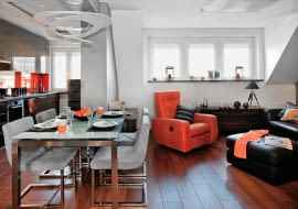 Pani Joanna pokochała swoje niewielkie mieszkanie jeszcze zanim się okazało, że można wykupić i zaadaptować poddasze. Dlaczego? Bo idealnie pasowało do koncepcji wystroju, jaką od dawna miała i którą zaakceptowała projektantka. W efekcie ulubione materiały wykończeniowe obu pań, czyli stal i beton, przemieniły tradycyjne wnętrze w nowoczesne, o modnym industrialnym charakterze. <BR /> MIESZKANIE. W otwartej części dziennej nowoczesna kuchnia kontrastuje z tradycyjnie urządzonym kącikiem wypoczynkowym, w którym ton narzuca fotel w mocnym pomarańczowym obiciu. Na podłodze w kuchni i przedpokoju położono terakotę, w części wypoczynkowej są deski z egzotycznego drewna doussie. Nad stołem zwiesza się efektowna lampa.