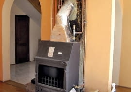 Widoczne naczynie wyrównawcze z zaworem pływakowym zamontowane nad korpusem kominka