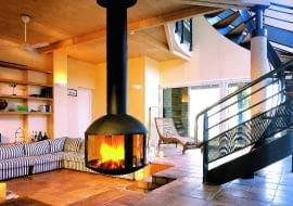 Podwieszony, a jednocześnie obrotowy wkład kominkowy ze stali. Palenisko otoczone jest czterema wygiętymi szybami