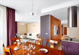 <b> RAZEM, A JEDNAK ODDZIELNIE. Wyraźny podział przestrzeni w części dziennej uzyskano dzięki zastosowaniu różnych barw, stylów i materiałów. Optyczne strefy wzmocniono, stawiając przegrody meblowe. W efekcie żaden z aneksów o odmiennych funkcjach nie koliduje ze sobą. </b> <BR /> Właścicielka mieszkania zdecydowała się na połączenie pokoju z kuchnią i przedpokojem, mimo obaw, że dwa ostatnie pomieszczenia będą dominować nad częścią salonową. Zawierzyła projektantce, która zapewniła ją, że tak się nie stanie. Kąt wypoczynkowy został oddzielony od aneksu kuchennego i od przedpokoju wysokimi ściankami, przy których zbudowano pojemne schowki. Jadalnię urządzono w obszernej wnęce niedaleko kuchni. Chociaż strefy jadalnej nie wydzielają dodatkowe przegrody, to jej odrębność jest wyraźna - podkreślają ją eleganckie stylizowane meble, które kontrastują z prostymi formami elementów wyposażenia w pozostałych częściach wnętrza. Kuchni nie widać ze strefy wypoczynkowej - zasłania ją wysoka zabudowa ze schowkami i urządzeniami AGD: piekarnikiem, kuchenką mikrofalową, ekspresem do kawy oraz lodówką i chłodziarką do wina. Strefę tę dodatkowo wyodrębnia podwieszany sufit i podłoga - płytki gresu dopasowane barwą do dębowego parkietu w salonie (gres położono też w części wejściowej przedpokoju).