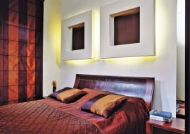 Łóżko stoi na ogół przy najbardziej widocznej ścianie w sypialni. Żal byłoby jej nie wykorzystać - do celów praktycznych albo dekoracyjnych, a najlepiej do obu jednocześnie. Zobaczcie, jak z głową zaaranżować miejsce za głową. <BR > Aranżacje wnętrz. W ramach ozdoby. Oryginalną dekoracją ściany są tu dwie grube ramy z płyty gipsowo-kartonowej. Ich środki wykończono tynkiem strukturalnym pomalowanym farbą w takim samym odcieniu jak meble i dodatki. Te nietypowe konstrukcje posłużyły również do ukrycia oświetlenia zastępującego gospodarzom lampki nocne.