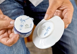 ...kiedy część wyprodukowanej porcelany wysyłano do Delft, miasta znanego z kunsztu holenderskich malarzy zdobiących słynny fajans. Na denku są więc sygnatury obydwu manufaktur.
