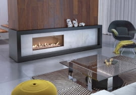 Kominki awangardowe często są duże, dlatego jednolita obudowa byłaby zbyt przytłaczająca. Łączy się więc materiały, takie jak różne rodzaje kamienia, drewno lub płytki ceramiczne. Na zdjęciu: zewnętrzna rama z granitu, wnętrze wyłożone szarym marmurem, cena od 6500 zł, KRATKI.PL