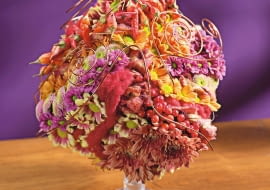 Orientalne kompozycje kwiatowe. Różne odmiany chryzantem gałązkowych zestawiono z papryczkami chili, kiśćmi kaliny koralowej i splotami czerwonej wełny. Całość ujęto w ażurową koronę z miedzianego drutu