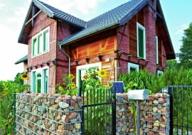 Dom Katarzyny i Kaja, otoczony słonecznikami, wrósł w sielski krajobraz mazowieckiej wsi. Uwagę zwraca oryginalna bryła z dwuspadowym dachem oraz gabiony wypełnione polnymi kamieniami.