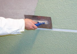 Nanoszenie tynku cienkowarstwowego w kolorze zielonym na ścianę pomiędzy boniami