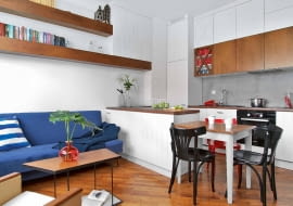 KANAPĘ Rafał wyszukał w internetowych ogłoszeniach, w dziale ,,oddam za darmo'. Miała ceglaste obicie i drewniane boki polakierowane na wysoki połysk. Tapicer pokrył ją tkaniną w odcieniu indygo, drewno zostało zmatowione. MEBLE KUCHENNE i zabudowę przy telewizorze zaprojektowała Karolina. Te same materiały (płyta MDF i fornir orzechowy) sprawiają, że wnętrze wygląda spójnie. Krzyżaki w przeszkleniach i frezowane fronty nawiązują do stylu marynistycznego. Podobne meble Rafał zobaczył kiedyś w jednej z żeglarskich tawern, co skrzętnie udokumentował.