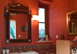 POWIEW WSCHODU. Punktem wyjścia w budowaniu atmosfery tej łazienki były podróże gospodarzy na Bliski i Daleki Wschód. Osiągając zamierzony efekt dekoracyjny, nie zaniedbano jednak funkcjonalności wnętrza. Są tu wszystkie niezbędne urządzenia sanitarne: kabina prysznicowa, duża umywalka, sedes. Do każdego z nich jest zapewniony swobodny dostęp. Pojemna szafka podumywalkowa z licznymi szufladami, zajmująca całą szerokość ściany, rozwiązuje problem przechowywania niezbędnych akcesoriów i ułatwia utrzymanie porządku. Początek aranżacji wnętrza dała mosiężna lampa sufitowa z Tajlandii. Dobrano do niej m.in. przywiezione z Egiptu lustro w ażurowej drewnianej ramie intarsjowanej masą perłową. W pomieszczeniu są dwa spore lustra i okno, dzięki czemu łazienka "nabrała oddechu".