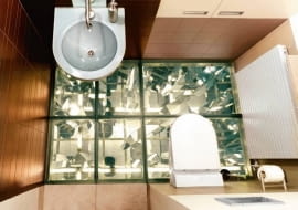 Aranżacje. Salon luster. Propozycja wyłącznie dla odważnych. Pierwsza warstwa podłogi to rozrzucone na szkle kawałki luster i fotografie. Właściwą posadzkę tworzą tafle hartowanego szkła ujęte w metalowe ramy. Całość migotliwa i zmienna niczym kalejdoskop.