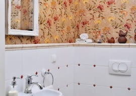 Do tej niewielkiej toalety dla gości wchodzi się bezpośrednio z salonu. Właścicielka chciała więc, by miała ona równie elegancki wystrój. Stylistka uznała, że duże zmiany wcale nie są konieczne. Wystarczy po prostu stylowo wykończyć pomieszczenie. <BR > Metamorfozy wnętrz. Fragmenty ścian nad płytkami ceramicznymi zostały oklejone dekoracyjną, imitującą wzorzysty jedwab tapetą. Powtarzają się na niej barwy podłogi i ceramicznych dekorów wstawionych między kafelki. Wytwornego charakteru wnętrzu dodała również listwa sztukateryjna pod sufitem oraz nowe akcesoria łazienkowe.
