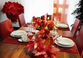 Nastrojowa dekoracja stołu. Poinsecje ułożono w niskich naczyniach z pojedynczymi goździkami i nerine.