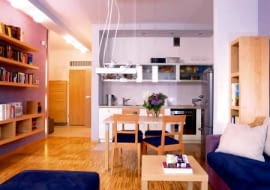 Aneks kuchenny jest integralną częścią salonu. Jasne, gładkie fronty szafek i przeszklone witrynki dają wrażenie lekkości, nie przytłaczają więc wnętrza.