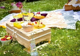 W roli stolika - skrzynka na owoce. 'Otulona' zgrzebną tkaniną i obwiązana wstążką zmieniła się w szykowny piknikowy mebelek.