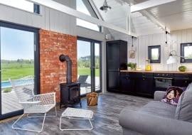 FUNKCJONALNOŚĆ GÓRĄ. (a dokładnie - dołem). Ze względów praktycznych właściciele zdecydowali się na podłogę z płytek ceramicznych imitujących stare deski (Cersanit). Wiernie oddają one kolor i fakturę drewna, które poszarzało pod wpływem czynników atmosferycznych. Są łatwe do utrzymania w czystości i trwałe (nie szkodzi im woda nanie- siona przez domowników z basenu). W minimalistycznym wnętrzu świetnie sprawdziły się lokalne materiały - drewno z pobliskiego tartaku oraz rozbiórkowa cegła.