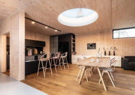 Urządzając wspólną, otwartą przestrzeń, zachowaj spójną aranżację. Wybierz tę samą formę wykończenia ścian, podobną kolorystykę i wstaw elementy łączące oba wnętrza. Tutaj są nimi, np. krzesła i hokery z tej samej kolekcji.