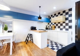 Elementem spajającym kuchnię z pozostałą częścią pomieszczenia jest ciąg szafek biegnących wysoko wzdłuż ściany.