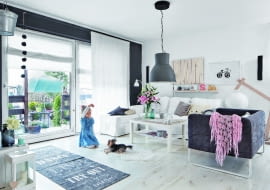 OD WIOSNY DO JESIENI. Naturalnym przedłużeniem salonu jest ogródek - wystarczy rozsunąć tarasowe drzwi. Stolik kawowy z IKEA nabrał szyku, gdy właściciele zamontowali na nim drewniany blat. Na podłodze leżą deski z bielonego dębu (Kronopol).